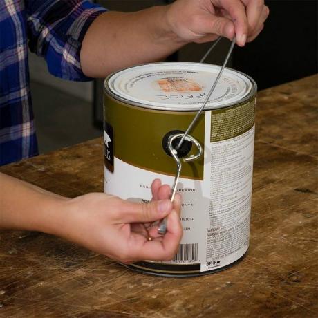 enganchar el abrelatas de pintura en el mango de la lata de pintura