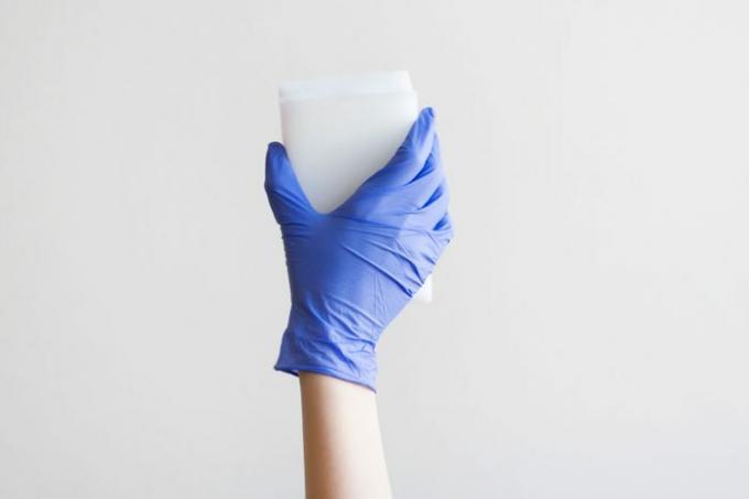 Kvinnehånd som holder en rengjøringssvamp isolert på en grå bakgrunn