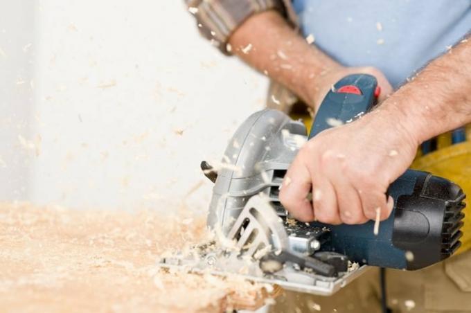 Heimwerken - Handwerker schneidet Holz mit Stichsäge in Werkstatt
