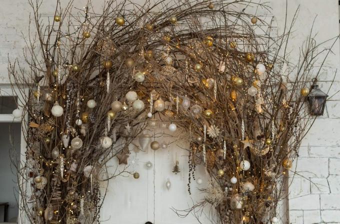 Weihnachtsschmuck mit natürlichen Details: Zweige mit Girlandenlichtern und Weihnachtskugeln. Öko-Dekor im Innenkonzept. Kreativer Weihnachtsbaum.