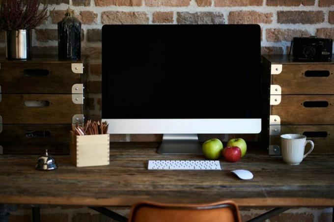 Desktop in modernem Loft-Interieur mit fortschrittlichem Computer für perfekte kreative freiberufliche Arbeit und stationärem PC, der in der Nähe einer Tasse Kaffee und Croissant zum Frühstück im Co-Working-Büro steht