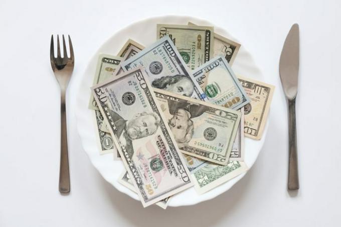 나이프와 포크가 있는 접시에 있는 미국 달러.