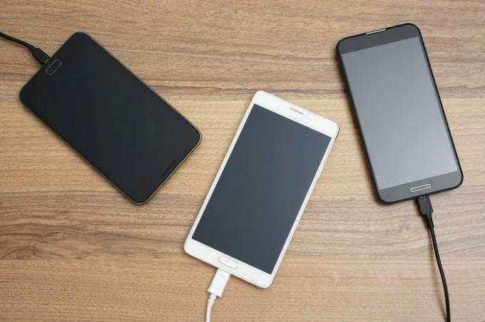 Мобилни смартфони се зареждат на дървено бюро