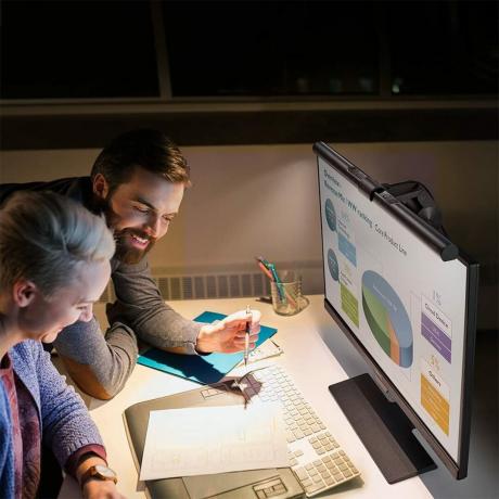 Bir masada birlikte çalışan iki kişiyle bir bilgisayarda Benq Screenbar Monitor Light