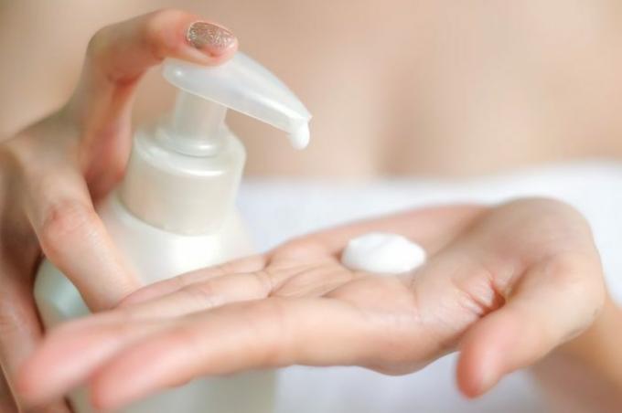 Primer plano de manos femeninas bombeando crema, loción de botella blanca, enfoque selectivo, concepto de cuidado del cuerpo de la piel de higiene, enfoque selectivo.