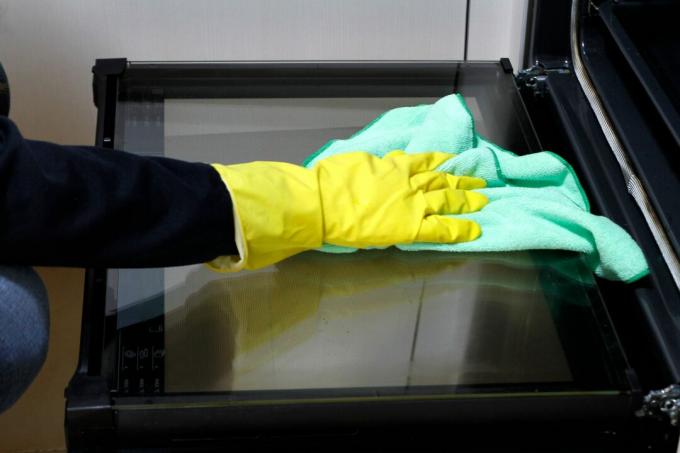 Close-up van de hand met rubberen handschoen reinigingsoven met rag