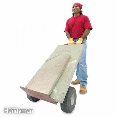 El hombre usa una plataforma rodante para mover piedras grandes.