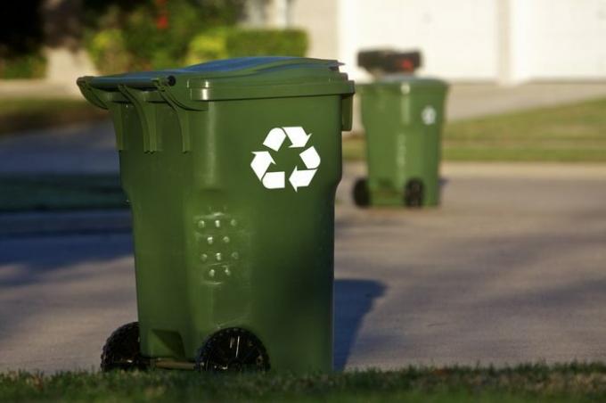 Contenedores de reciclaje verdes alinean una calle de vecindario