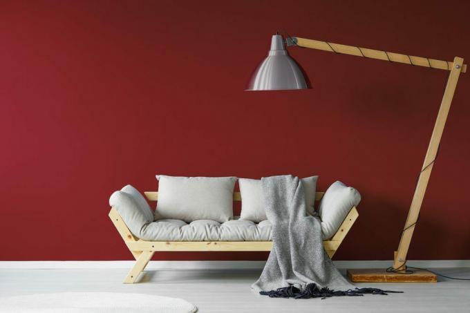 Удобан кауч са великом лампом која стоји изнад њега у минималистичком ентеријеру дневне собе 