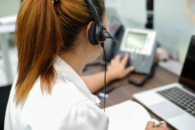 De cerca, céntrese en los auriculares de la respuesta de respuesta del centro de llamadas asiático o utilice el teléfono que trabaja en el concepto de sala de operaciones.