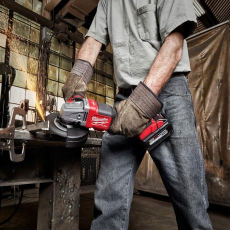 Homem moendo metal com um moedor milwaukee sem fio | Dicas profissionais de construção