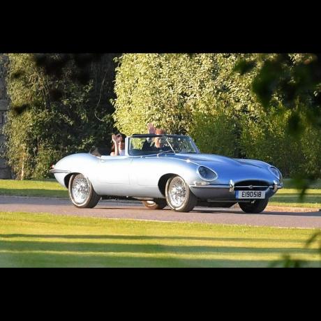 Prins Harry og Meghan Markle vinker mens de kjører bort i en Jaguar E-type etter bryllupet