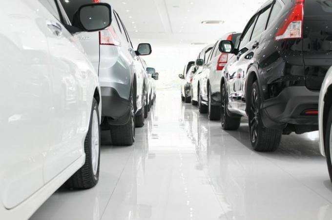 En rad med nye biler parkert ved et bilforhandlerlager, Nye japanske biler i utstillingslokale for showkunder.