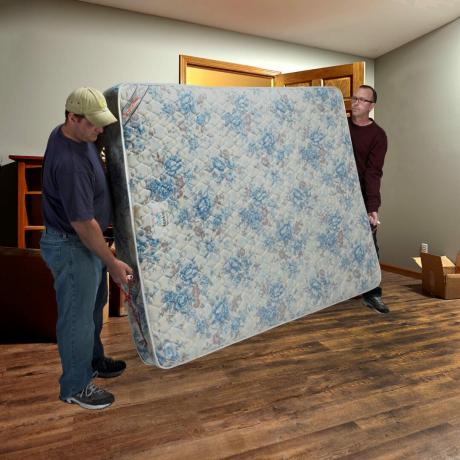 twee mannen verplaatsen een matras met een draagdoek